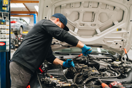 Mechanic at Bavarium Autoworks in Mountain View, CA, repairs vehicle engine using a wrench.