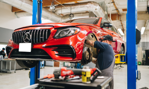 Mechanic in Mountain View inspects and repairs vehicle suspension on a red Mercedes after removing the wheels.