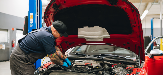 Auto technician at Bavarium Autoworks in Mountain View, CA, perform diagnostic inspection on a red Audi.